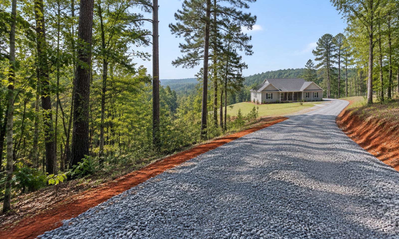 New gravel driveway curving toward a home among North Carolina hardwoods and pines
